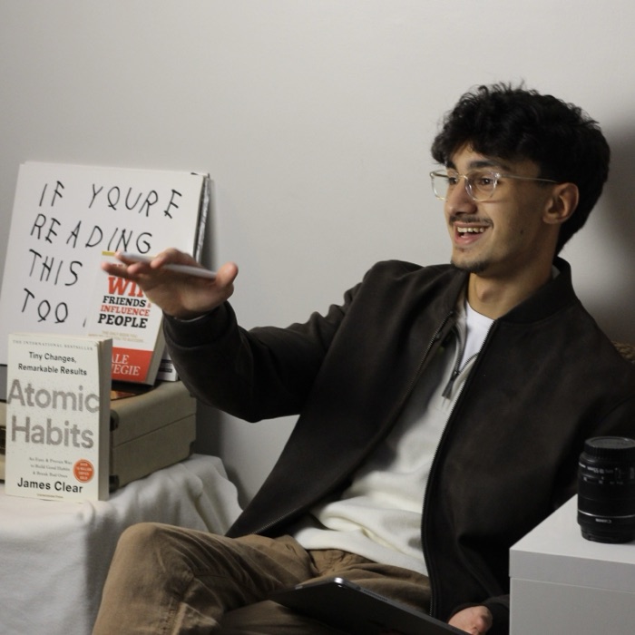 Khaled AlHaddad, mid-sentence, seated with a stack of books beside him